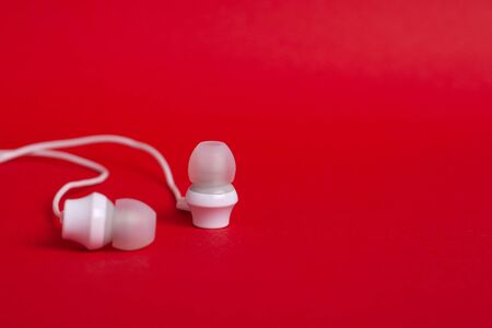 Concept: white headphones (earphones) on a red background with copyspace close upの写真素材