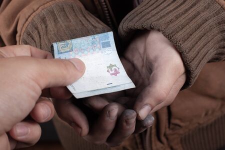 the guy brought a donation for the beg, the beggar receives cash in the palm of his hand.