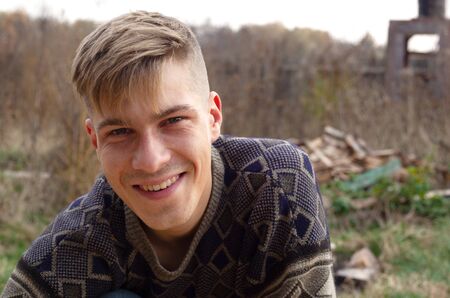 portrait young guy 20-21 old years in a sweater outdoors smiling at the camera closeup