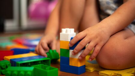 A child sitting on the floor plays with a children colorful constructor.