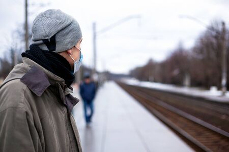 the guy in the respirator is waiting for the train. Concept: colds, flu