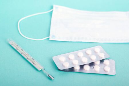 high temperature , high fever for colds. antiviral medical products. pills, thermometer, mask on a...