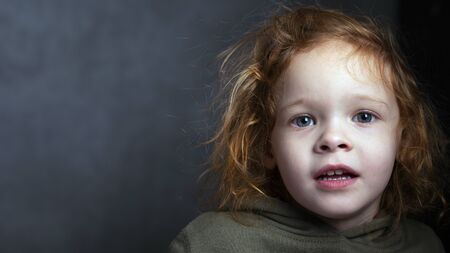 cute red-haired little girl portrait on a gray background. redhead child .