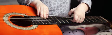 guitar and small children hands. music themed panoramic shot.