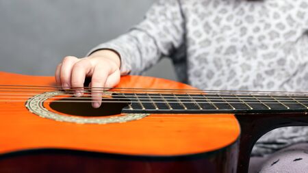 little girl and acoustic guitar. child learn to play the guitar.