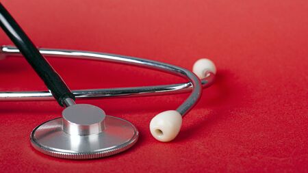 stethoscope on red background closeup. heart rate medical device.の写真素材
