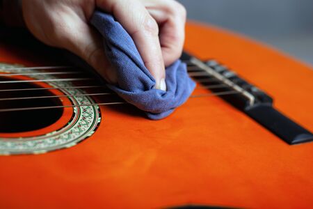 cleaning the acoustic guitar body with a clean rag.の写真素材