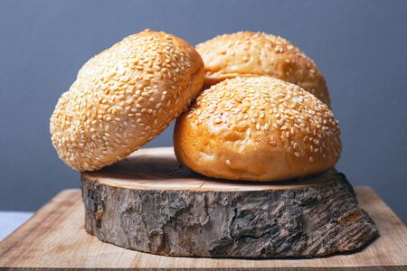 buns for making burgers with sesame seeds on a wooden stand on a gray background close-up.の写真素材