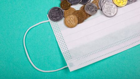 rising prices for medical masks, protective mask and a handful of coins on a blue background. rise in price of medicine due to the pandemic coronavirus covid-19.の写真素材