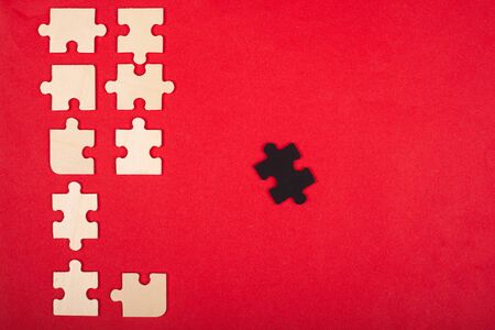 wooden puzzles of white and black color on a red background top view. stand out, leader.の写真素材