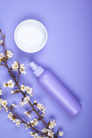 bottles with body care cosmetics with white flowers on violet background top view.の写真素材