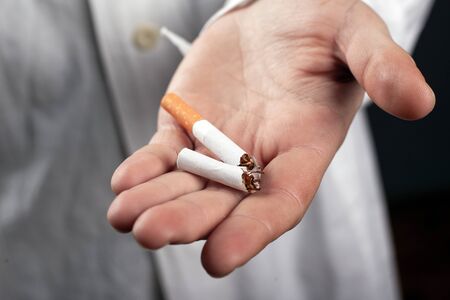 broken cigarette in the hand of a doctor close-up. health hazards from smoking tobacco.の写真素材