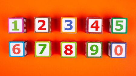 wooden cubes with numbers exactly stacked on an orange background top view close-up developing a toy.の写真素材