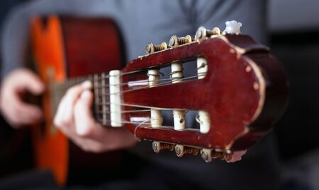 guitarist's hand squeezes fingers on the chords of an acoustic guitar.