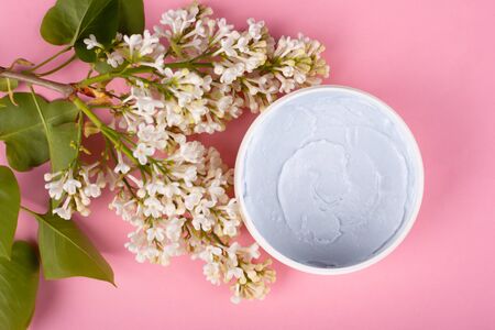body scrub on a pink background with flowers of lilac top view close-up. skin care cosmetics, beauty, spa.の写真素材