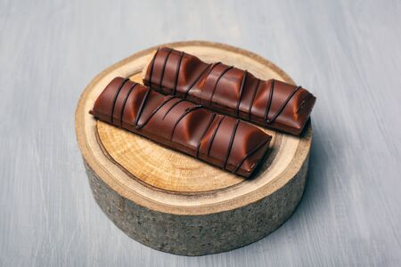 chocolate sticks on a forest wooden stand on a gray background sweets for joy close-up.