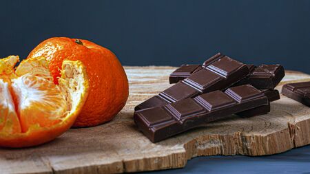 chocolate and tangerines on wood board and dark background closeup.の写真素材