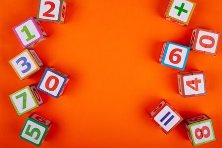 Wooden cubes with numbers on an orange background top view close-upの写真素材