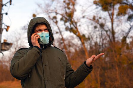a man in a medical mask is indignantly talking on the phone epidemic situation with coronavirus...