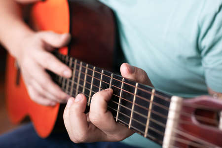 playing the acoustic guitar close-up, hand grips the chord, playing a musical instrument.