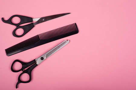 haircutting tools on a pink background, copy space, straight and thinning shears with comb.の写真素材