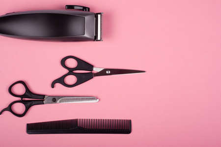 hair clipper, straight and thinning barber scissors and comb on a pink background top view, copy space. hairdressing tools.の写真素材