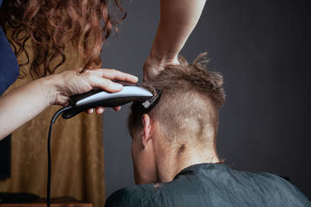 woman cuts a man with a trimmer in a hairdresser. stylish haircut.

の写真素材
