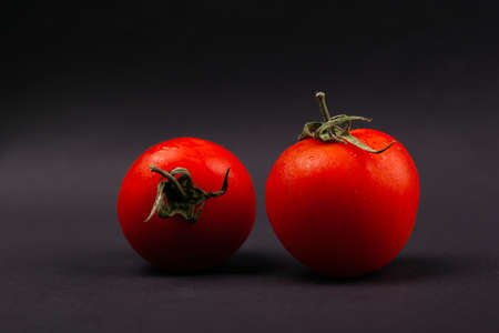 two red cherry tomatoes on a dark gray background.
の写真素材