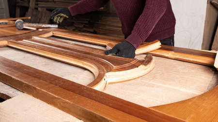 the master is engaged in the restoration of the wooden door in the workshopの写真素材