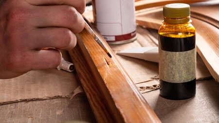 the master paints the place of the defect on the wooden door with varnish, restoration of an old...
