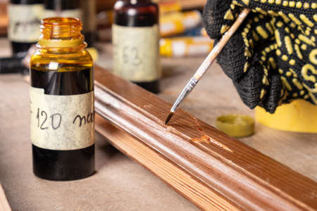 the master paints the place of the defect on the wooden door with varnish, restoration of an old wooden door close-upの写真素材