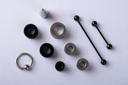ear jewelry, ear tunnels black and silver with dilator and piercing stacked on white background top...