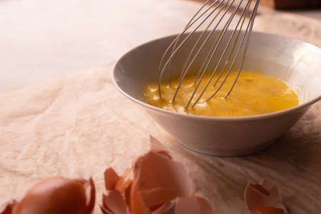 beat eggs in a plate with a whisk closeup.