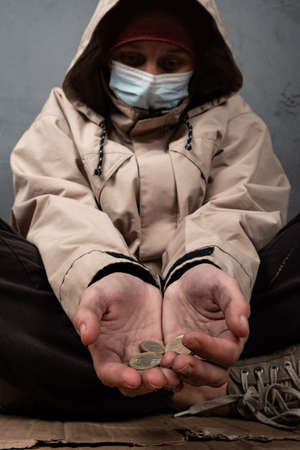 beggar girl in a medical mask asks for help, coins in the hands of a homeless woman.