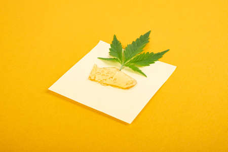 high thc, pieces of golden yellow cannabis wax and green leaf, marijuana concentrate.の写真素材