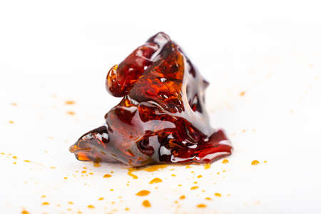 a piece of dark amber cannabis wax concentrate close up on white paperの写真素材