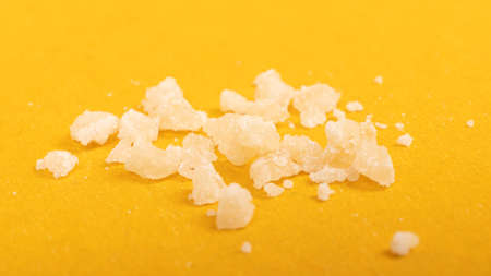 crystal pieces wax of marijuana concentrate, cannabis dab on yellow background