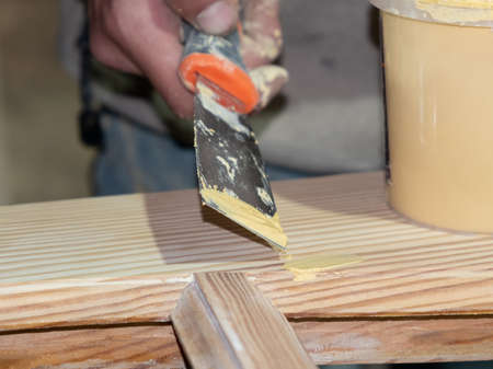 hand with putty spatula wooden crafts, door restoration