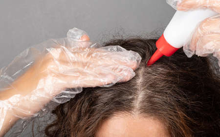 a woman applies dye to the roots of her hair paints gray gray hair