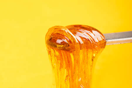 amber yellow cannabis wax concentrate dripping from the dabbing tool close-upの写真素材
