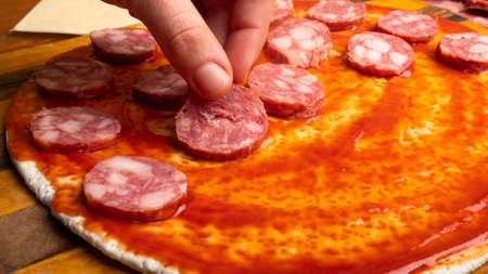 pizza with sausage and tomato sauce cookingの写真素材