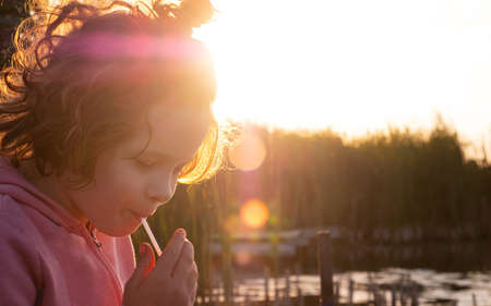 Portrait of a little girl against the backdrop of the evening sun, outdoor recreation by the riverの写真素材