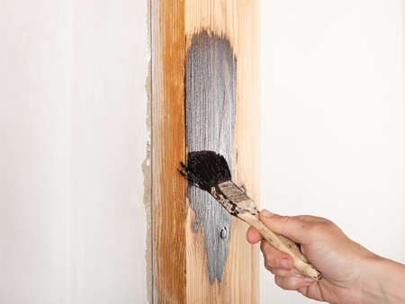carpenter with brush painting a wooden doorway, furniture restoration