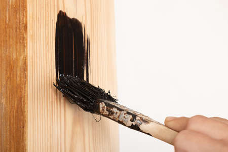 painting brush a wooden surface with a dark varnish
