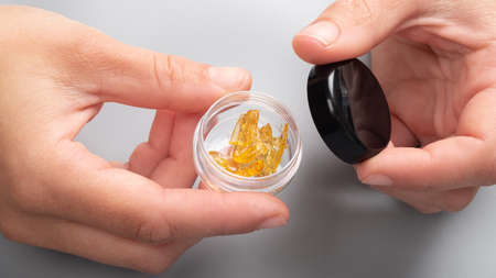 golden cannabis wax in female hands in a box, strong thc extractの写真素材