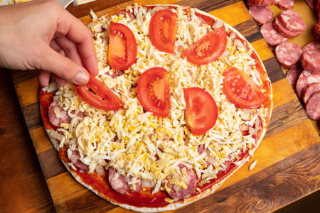 cooking pizza with tomatoes and sausage.