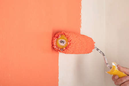 peach wall painting, hand with roller the concept of renovation in the roomの写真素材