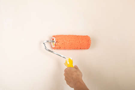 paint roller in the workers hand on the background of the wallの写真素材
