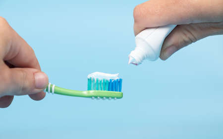 toothpaste is applied to the toothbrush,tooth brushing in hand on blue background
