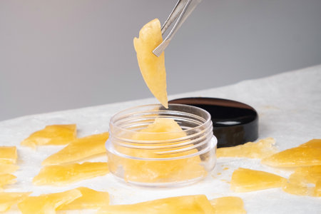 box of golden extract medical marijuana wax and tweezers in handの写真素材